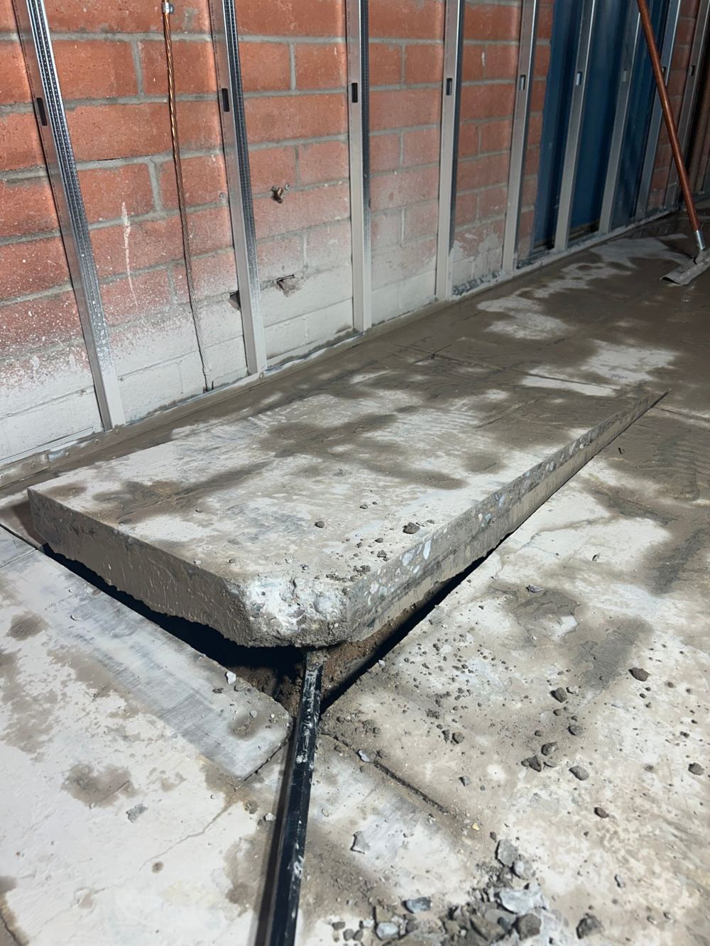 Saw-cut concrete slab section lifted out, showing clean straight edges